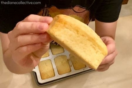 Mini lemon loaf held up to show side view with golden brown edges and soft crumb